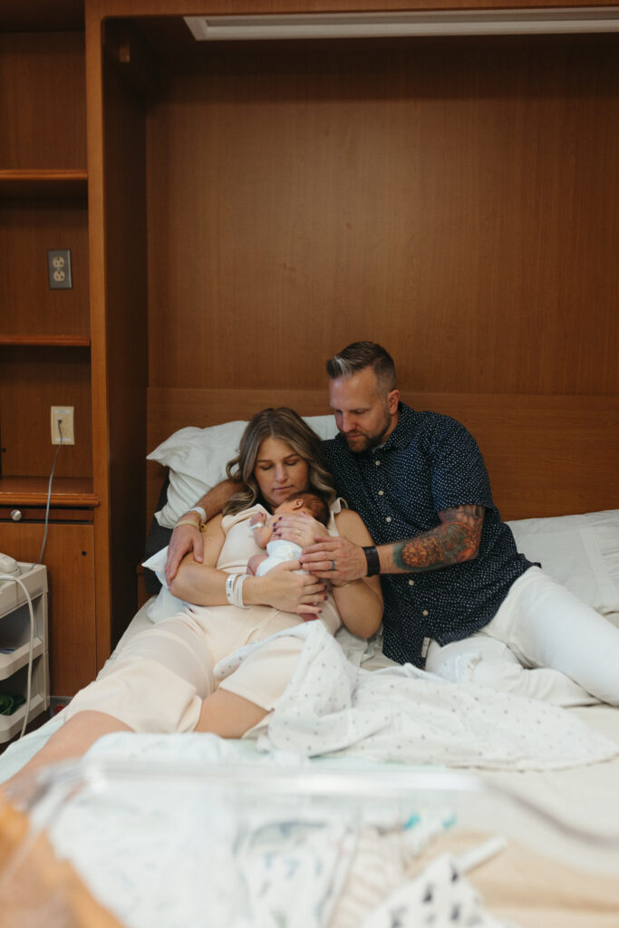 Dad and Mom sitting in hospital bed with baby at St Lukes Hospital in Cedar Rapids