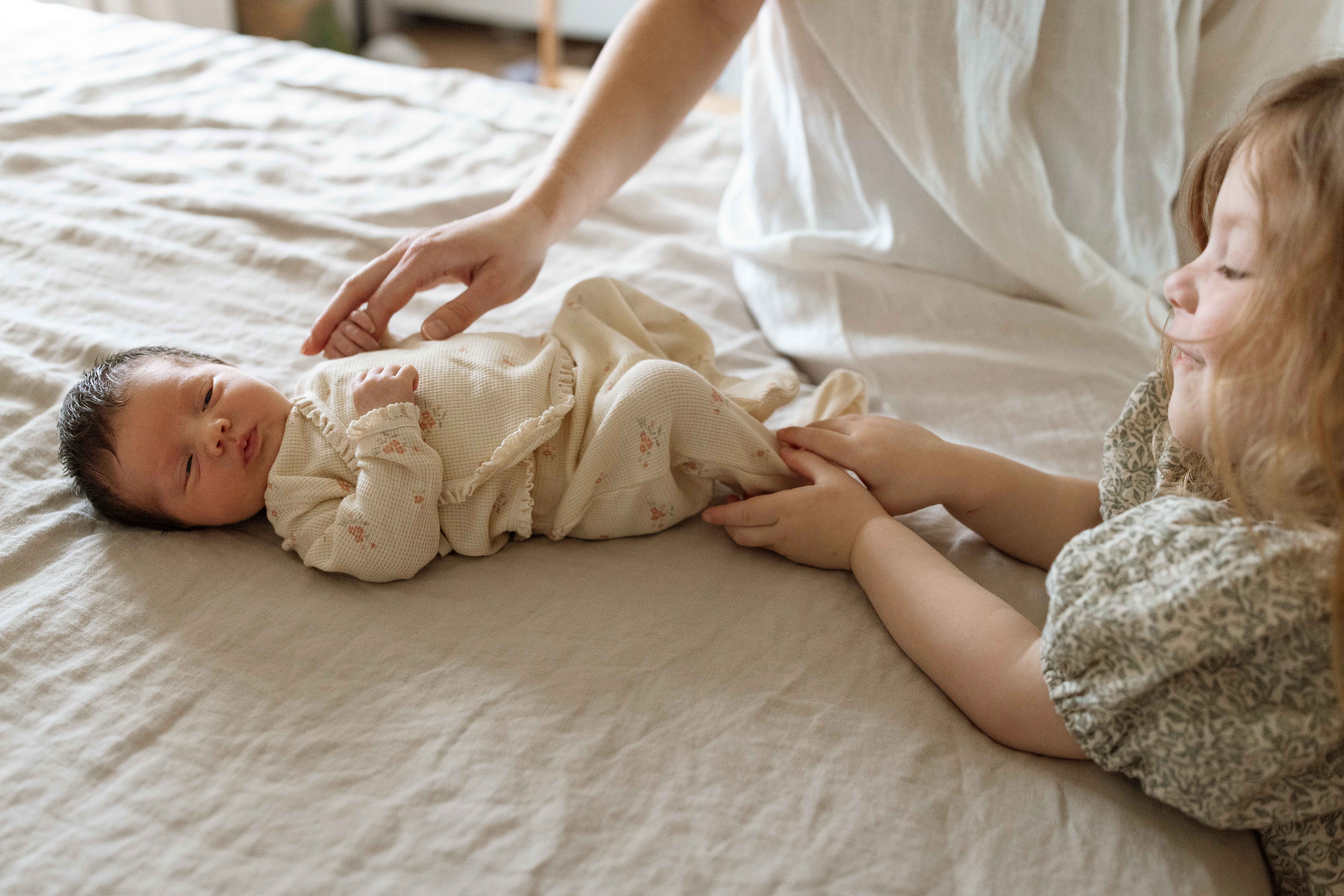 mom and sibling with newborn baby at home