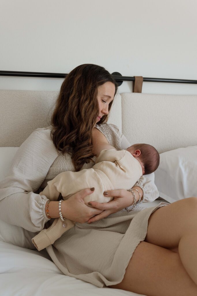 mother breastfeeding newborn during newborn photography session iowa city iowa